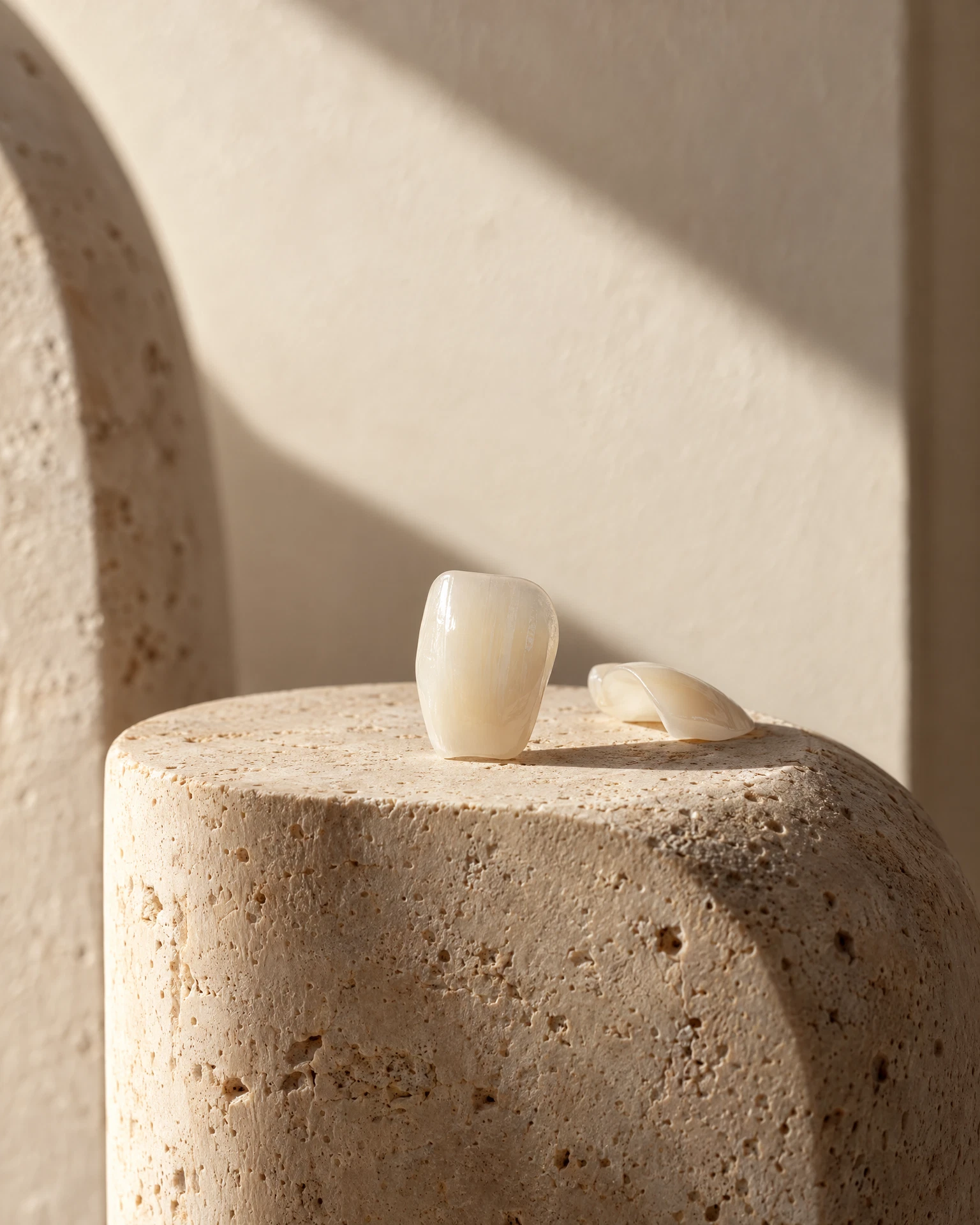 Editorial material study of ivory porcelain veneer shells on a travertine pedestal